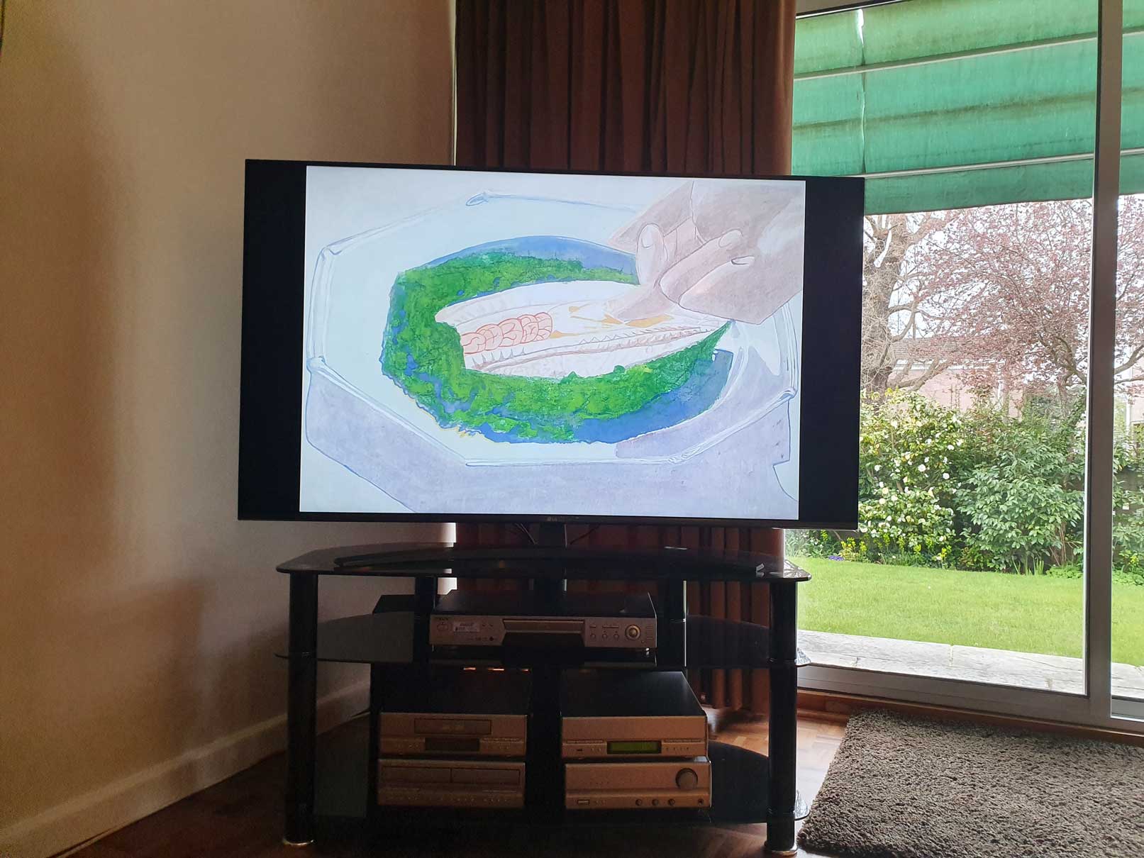 An image of a painting by the artist Alice Mendelowitz is displayed on a TV in the corner of a room, next to a glass sliding door that leads to a garden.