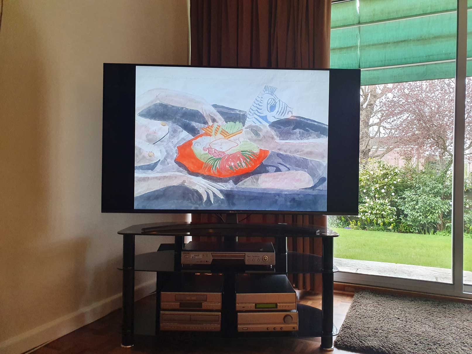 An image of a painting by the artist Alice Mendelowitz is displayed on a TV in the corner of a room, next to a glass sliding door that leads to a garden.