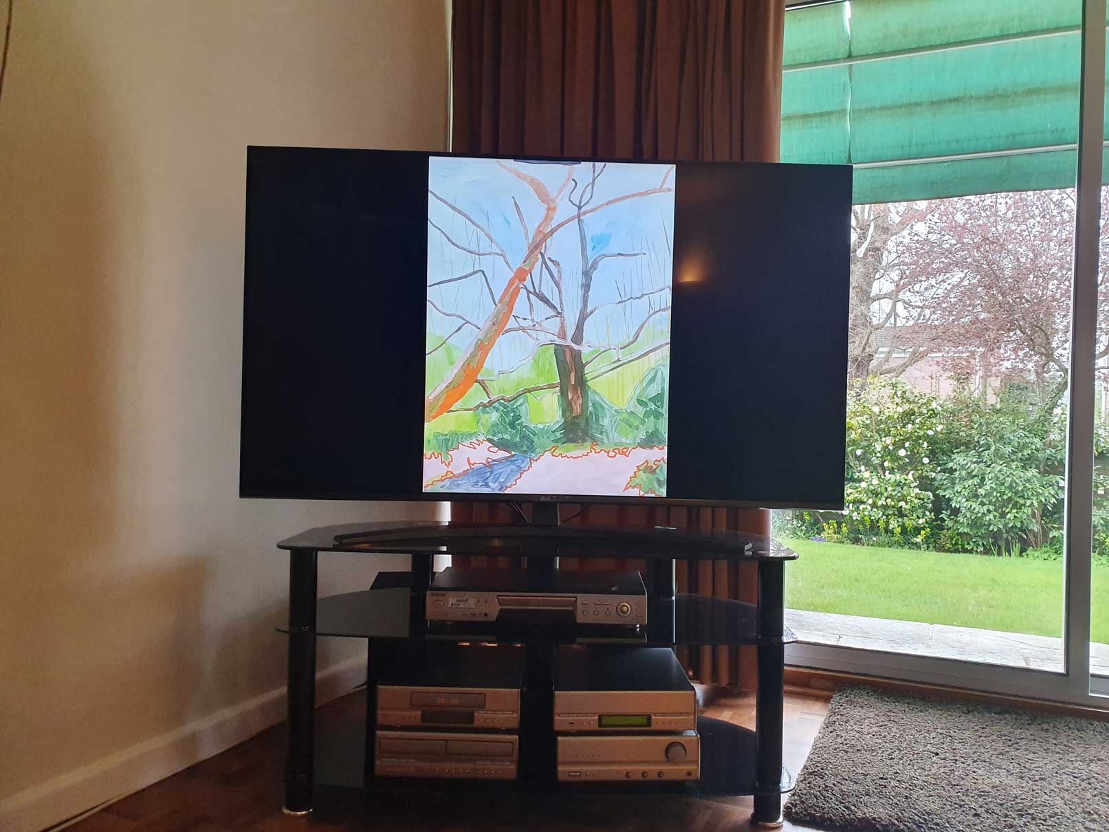 An image of a painting by the artist Alice Mendelowitz is displayed on a TV in the corner of a room, next to a glass sliding door that leads to a garden.