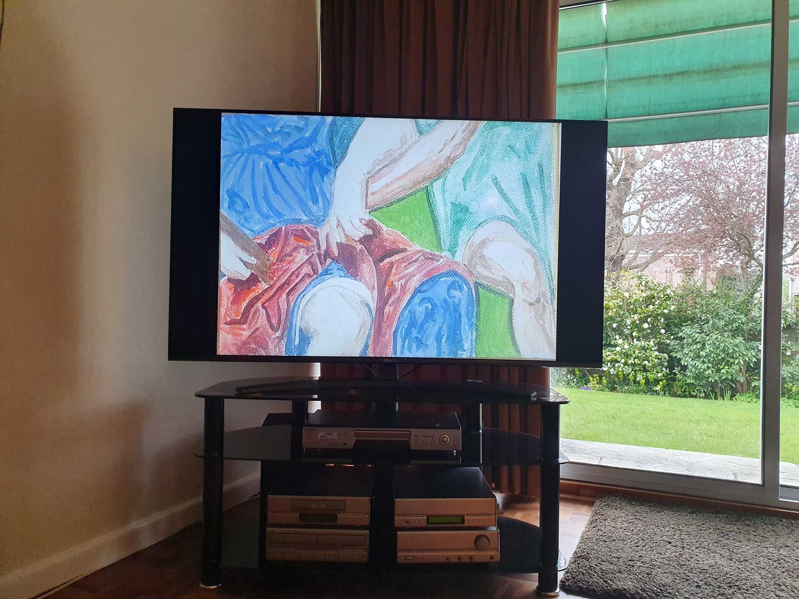 An image of a painting by the artist Alice Mendelowitz is displayed on a TV in the corner of a room, next to a glass sliding door that leads to a garden.