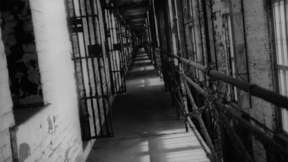 black and white film still of prison architecture in disrepair, peeling paint and rust